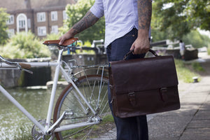 Bunbury Classic dark brown Leather Satchel on a white bicycle with model standing by