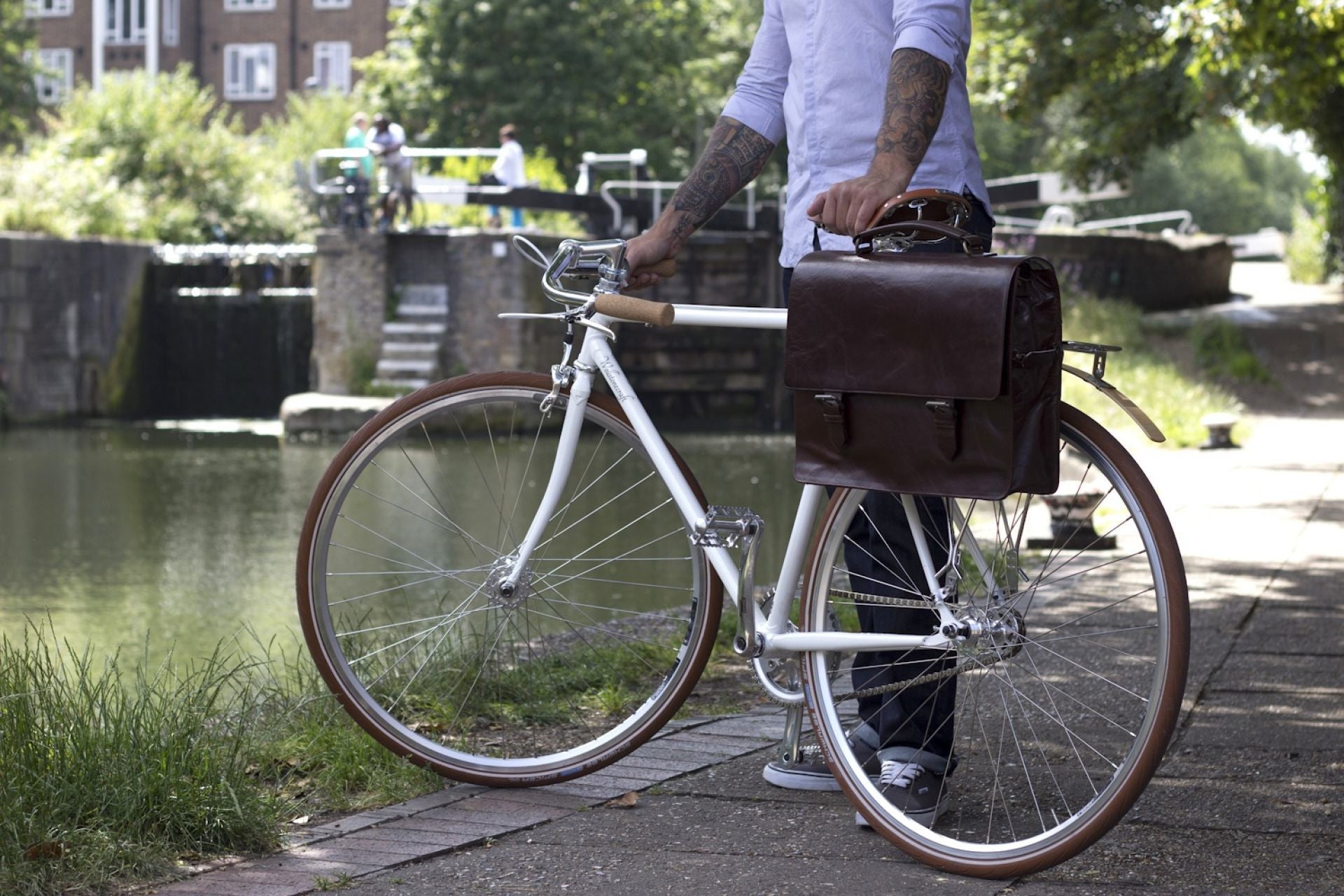 Bunbury Classic dark brown Leather Satchel on a white bicycle with model standing by