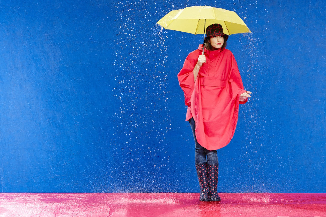 Photo of Model wearing a HappyRainyDays Rain Cape holding an umbrella