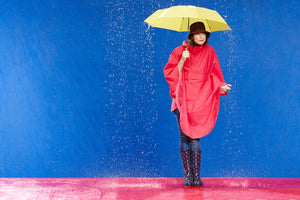 Photo of Model wearing a HappyRainyDays Rain Cape holding an umbrella